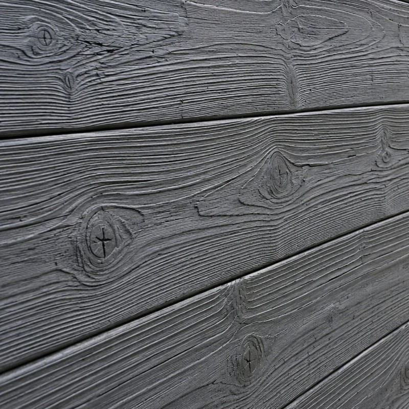 Gros plan sur le relief et la texture d'une clôture béton imitation lames bois.